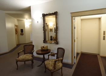 A hallway with a table and chairs and a mirror on the wall.